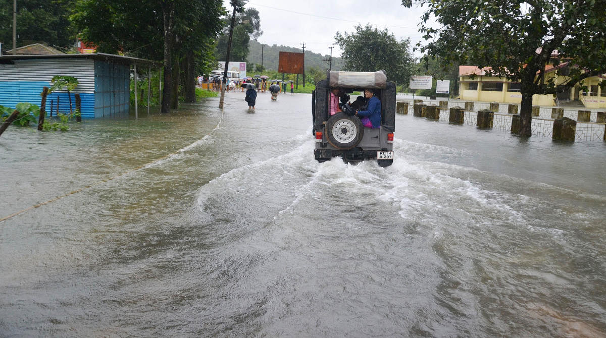 A jeep carries passengers on a flooded road in Bhagamandala. DH Photo