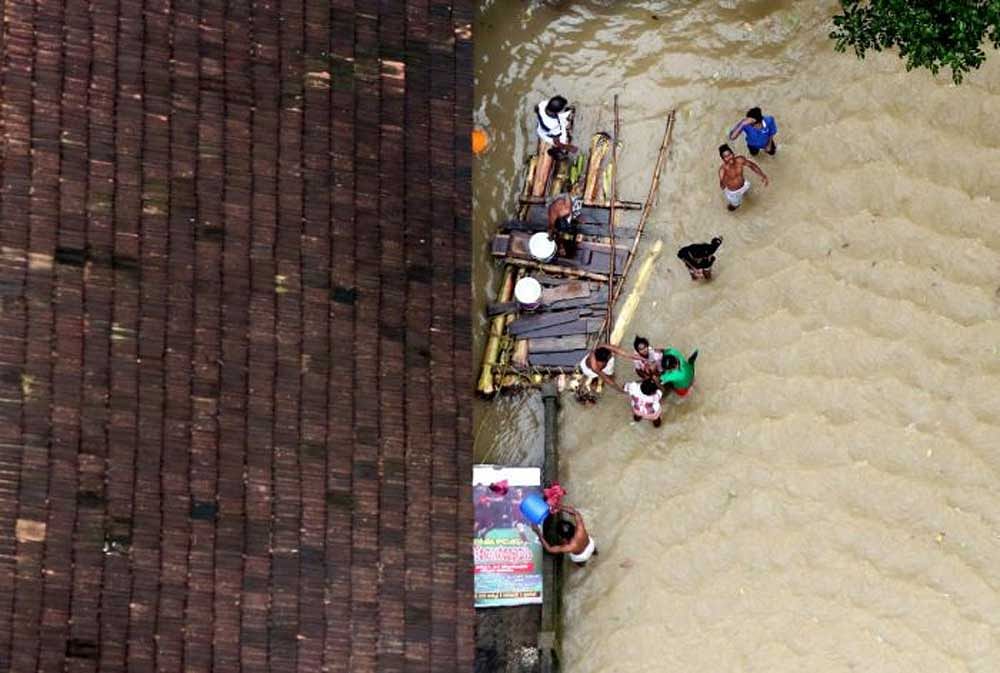 People wait for aid next to makeshift raft at a flooded area in Kerala on Sunday. Reuters Photo