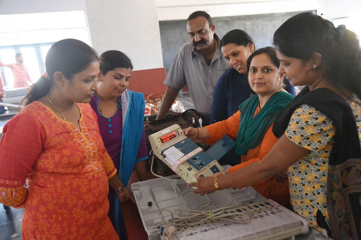 Polling booth personnel check the control unit during the mustering process in Madikeri on Wednesday.