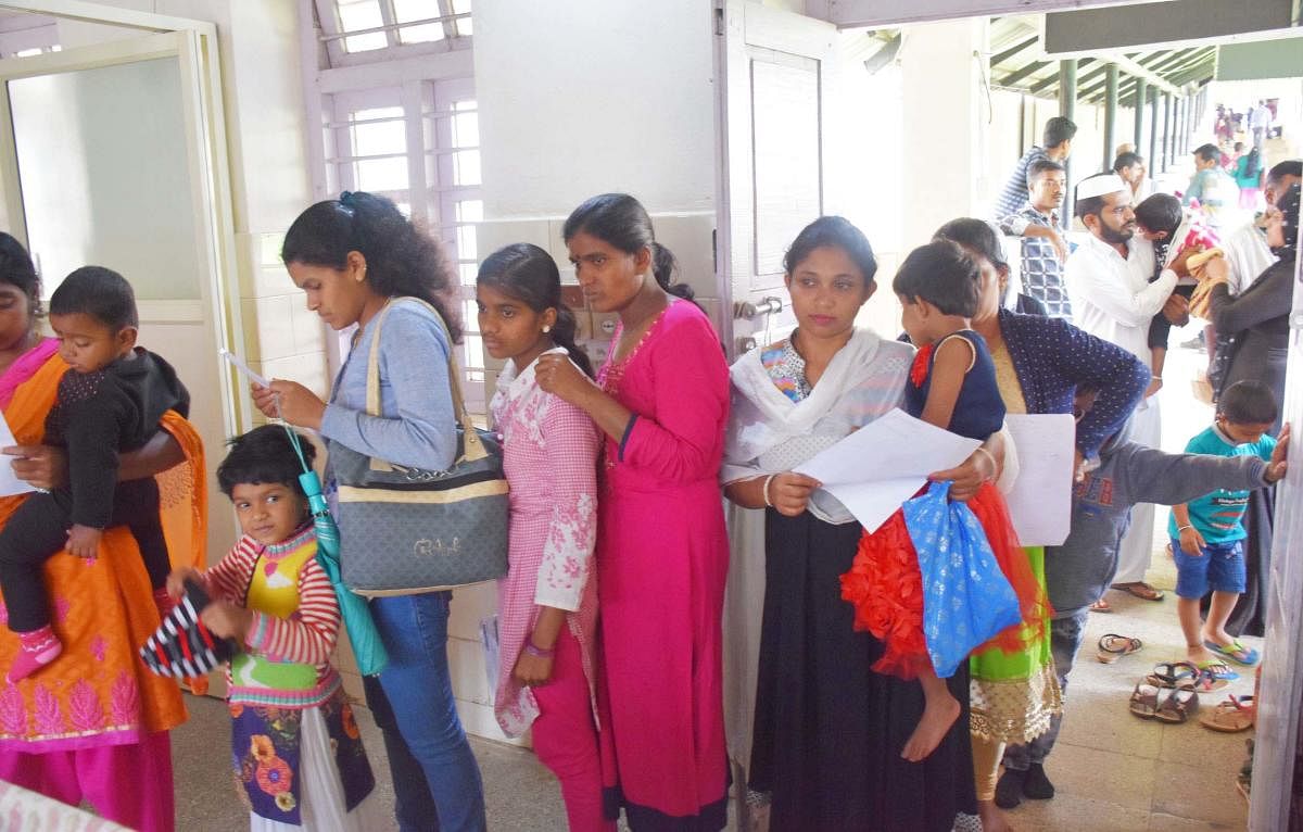 Parents wait with their children in a queue at District Children's Hospital in Madikeri.