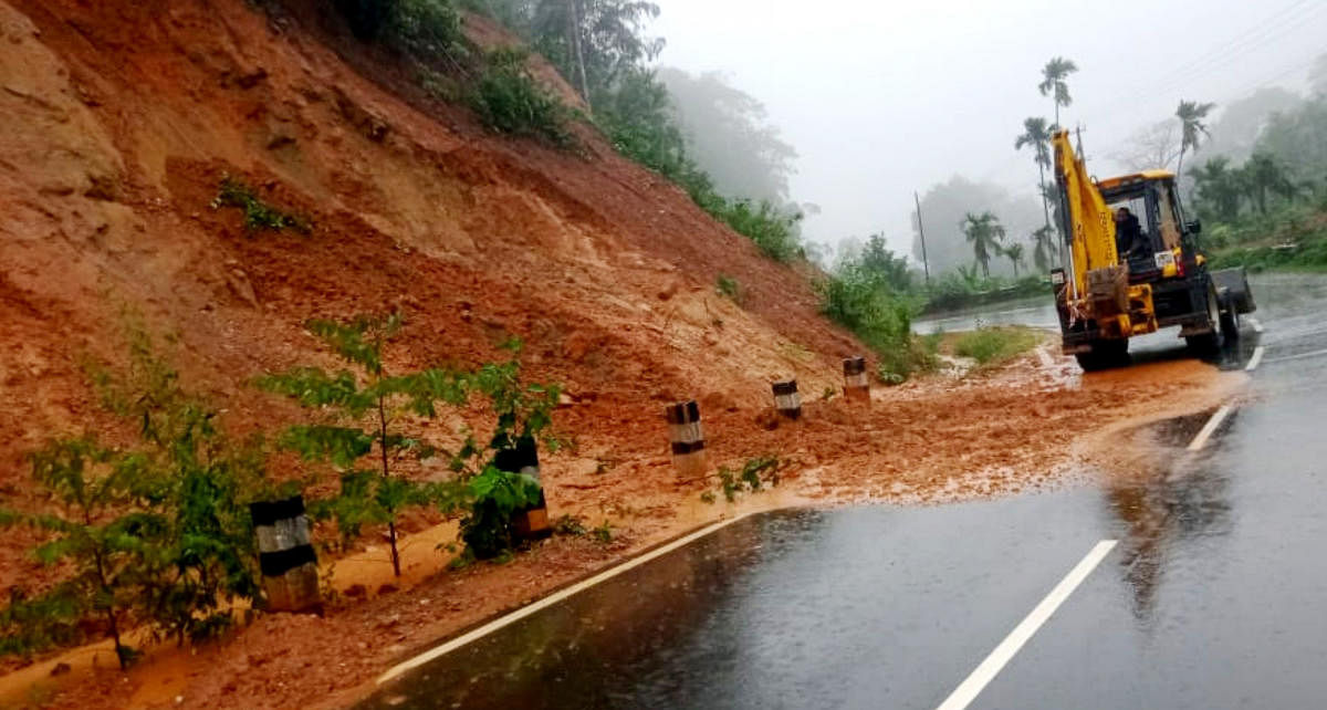 An earthmover clears the soil following a landslide on NH 275 near Madenadu in Kodagu district.