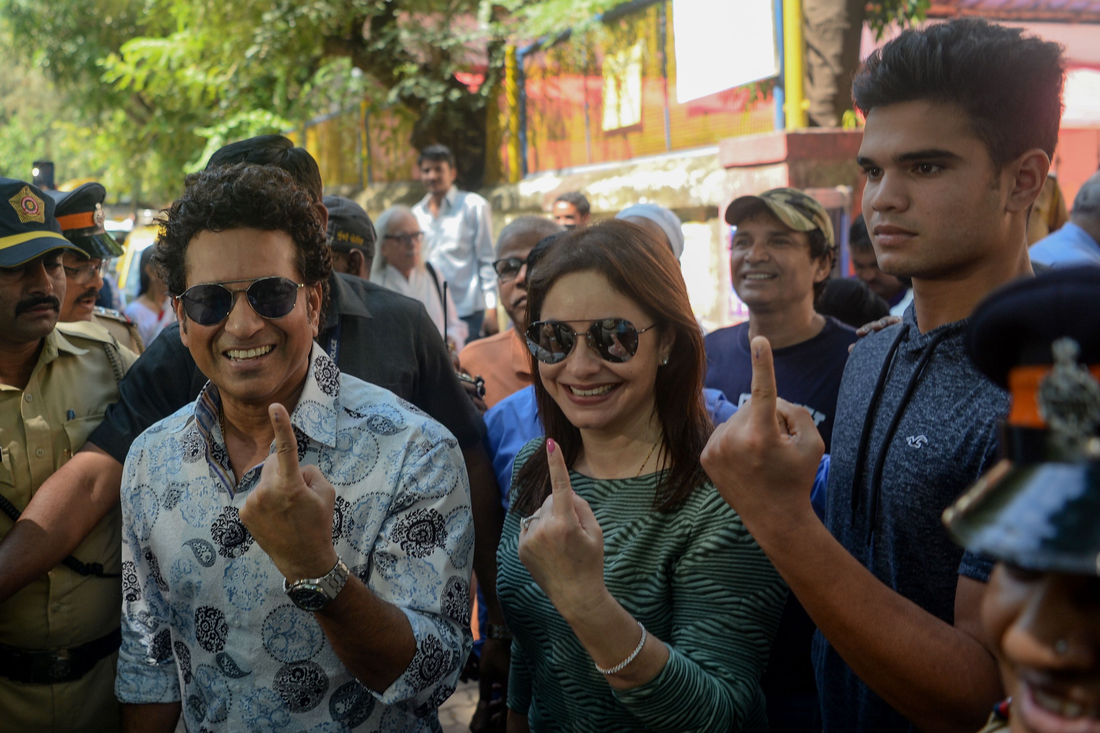 Former cricketer and captain Sachin Tendulkar (L) shows his inked finger after casting his vote along with his wife Anjali Tendulkar (C) and his son Arjun Tendulkar (R) during the state assembly election in Mumbai. (AFP Photo)