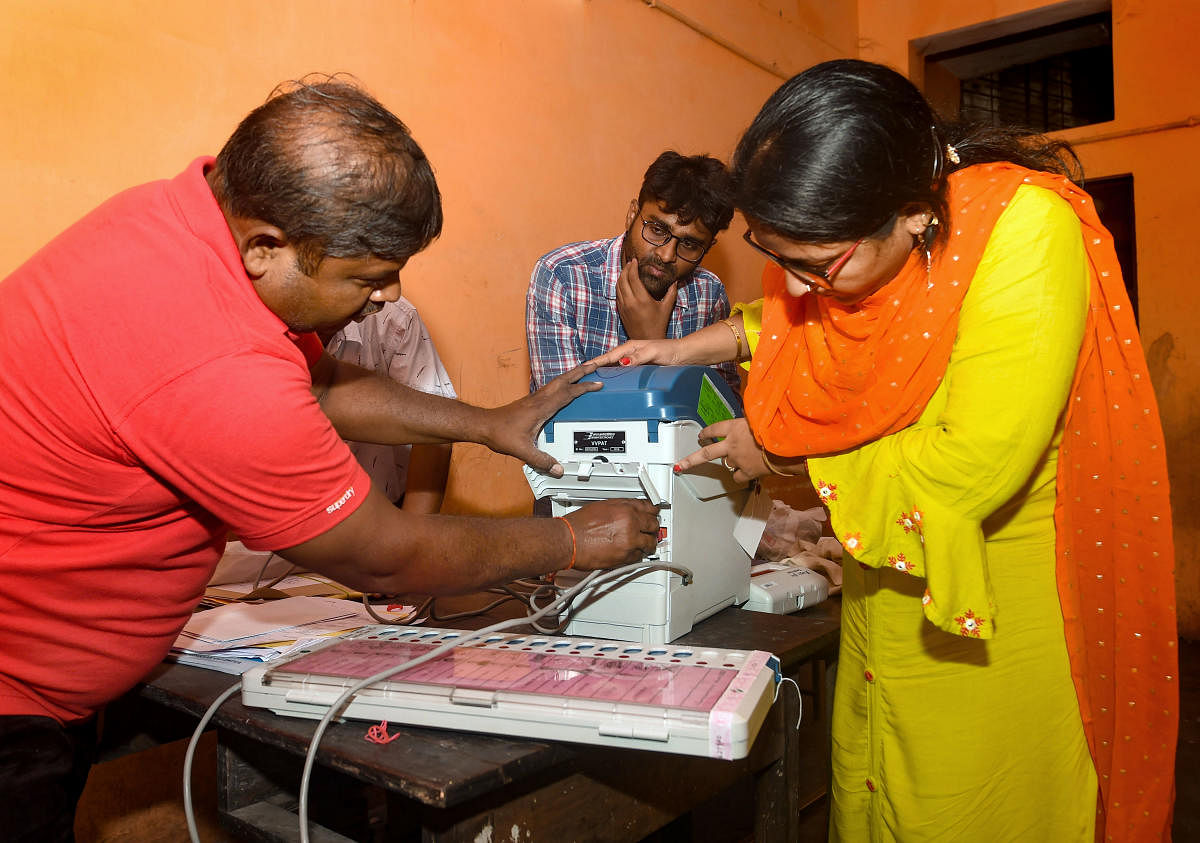 Polling officials set EVMs at a booth in Lucknow Cantt. Assembly Constituency in Uttar Pradesh on the eve of by-polls, Sunday. (PTI Photo)