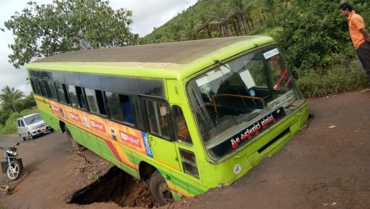 An NWKRTC bus stuck in a trench after road caved in due to heavy rain, near Chikkadinni village in Hukkeri talukof Belagavi district.