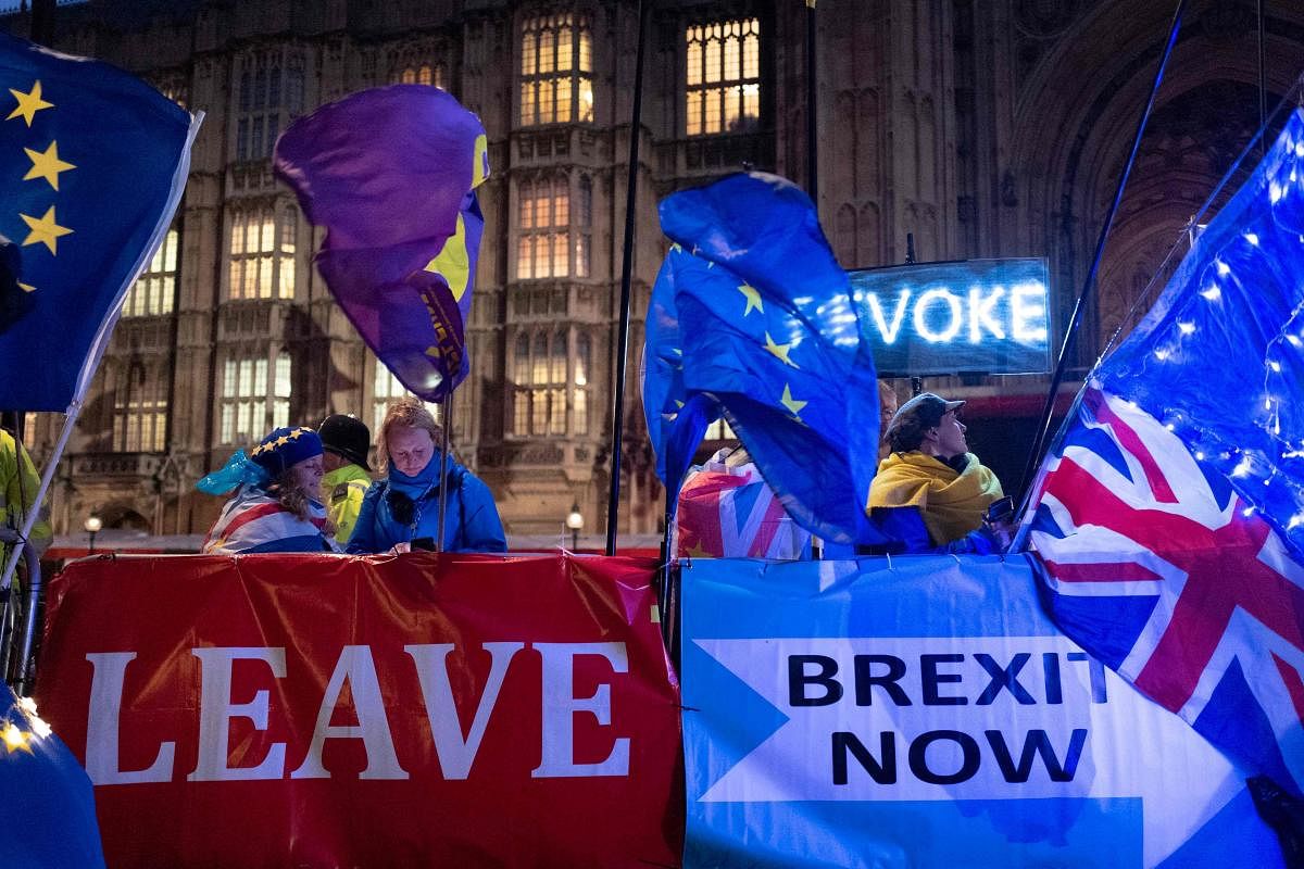 Pro and anti-Brexit aprotesters wave flags and hold banners as they demonstrate outside of the Houses of Parliament in central London. (AFP  Photo)