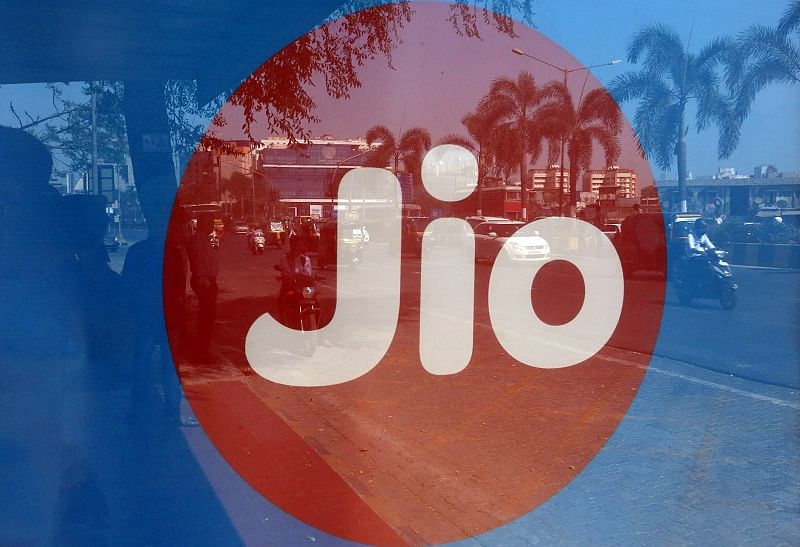 Commuters' reflections are seen on an advertisement for Reliance Industries' Jio telecoms business at a bus stop in Mumbai. (Reuters Photo)