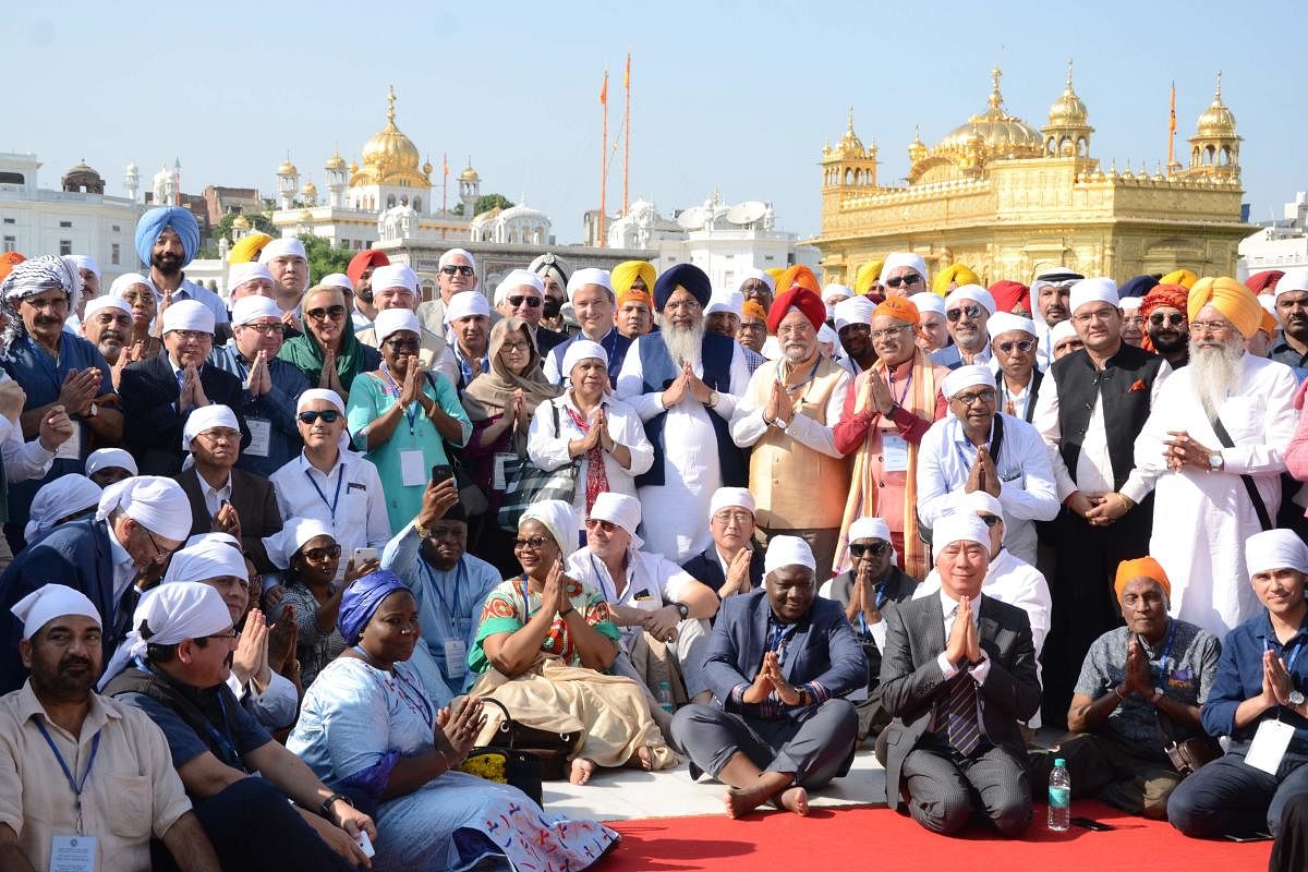 Minister of State for Civil Aviation Hardeep Singh Puri (centre with red turban) poses for a picture with diplomats and ambassadors of 91 countries as they pay their respects at the Golden temple in Amritsar on October 22, 2019.  (Photo by NARINDER NANU / AFP)