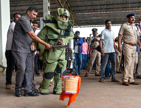 A bomb disposal squad personnel carries a bucket, which contained a parcel allegedly triggering a minor blast, to a safer place, at Hubballi railway station on October 21, 2019. (PTI Photo)