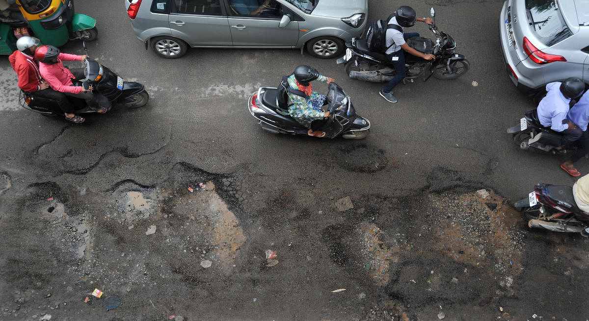 Following heavy rains, several roads in the city are pothole-ridden. Pictured: Commuters try to avoid puddle filled pothole stretch on the busy Kodichikkanahalli Road, Bilekahalli in Bengaluru on Tuesday. | DH Photo: Pushkar V