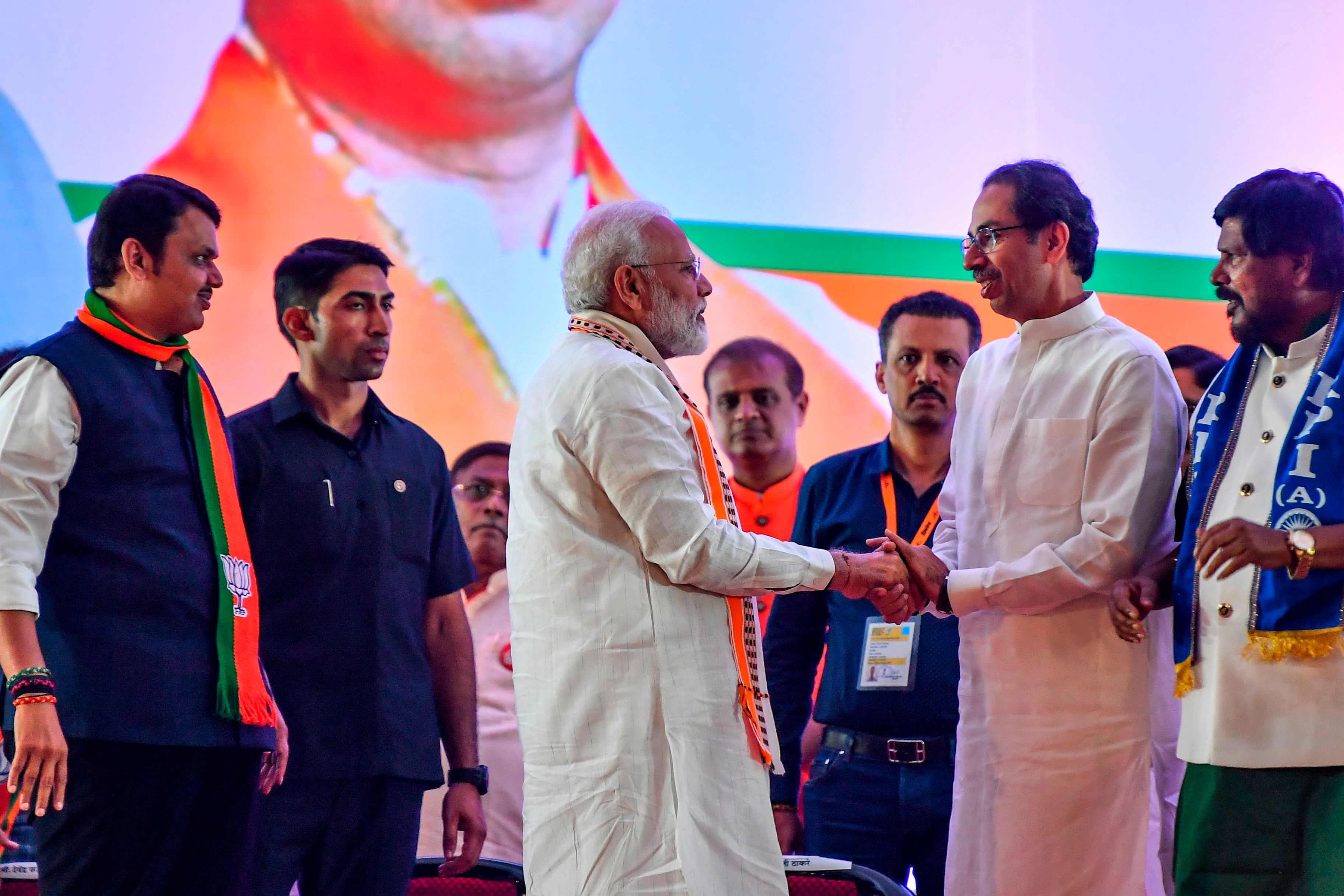 India's Prime Minister Narendra Modi (C) shakes hands with Hindu right-wing party Shiv Sena Chief Uddhav Thackeray (2R) as they attend a public rally in the run up to the Maharashtra. (AFP Photo)