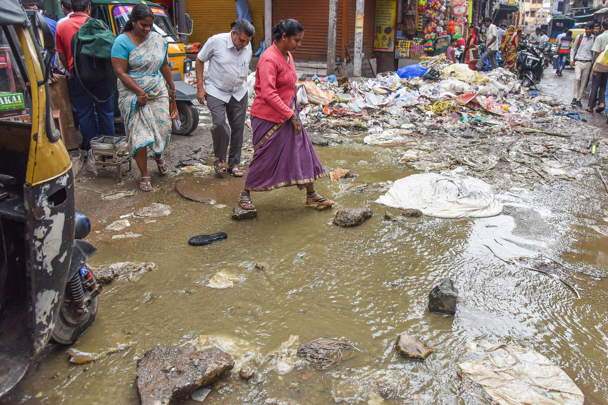 People suffer to cross the road, due to sewage under ground pipe is block from last twenty days and water flowing on the road at Kumbarpet OK road, Avenue road cross in Bengaluru on Friday. DH Photo