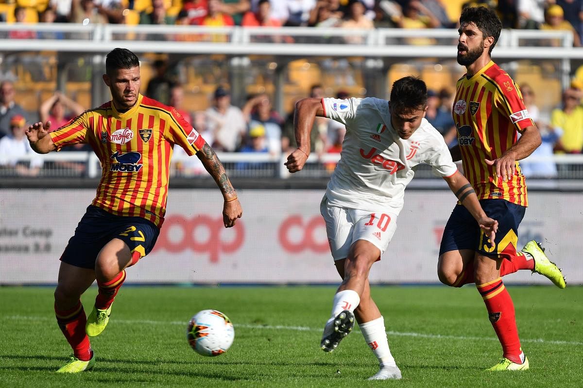 Juventus' Argentine forward Paulo Dybala (C) shoots on goal past Lecce's Italian defender Marco Calderoni (L) during the Italian Serie A footbal match Lecce vs Juventus on October 26, 2019 at the Stadio Comunlae Via del Mare in Lecce. (Photo by Alberto PIZZOLI / AFP)
