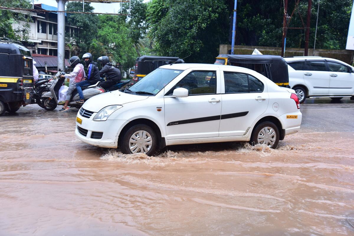 Vehicles wade through the rainwater on a road at Bejai in Mangaluru on Saturday.