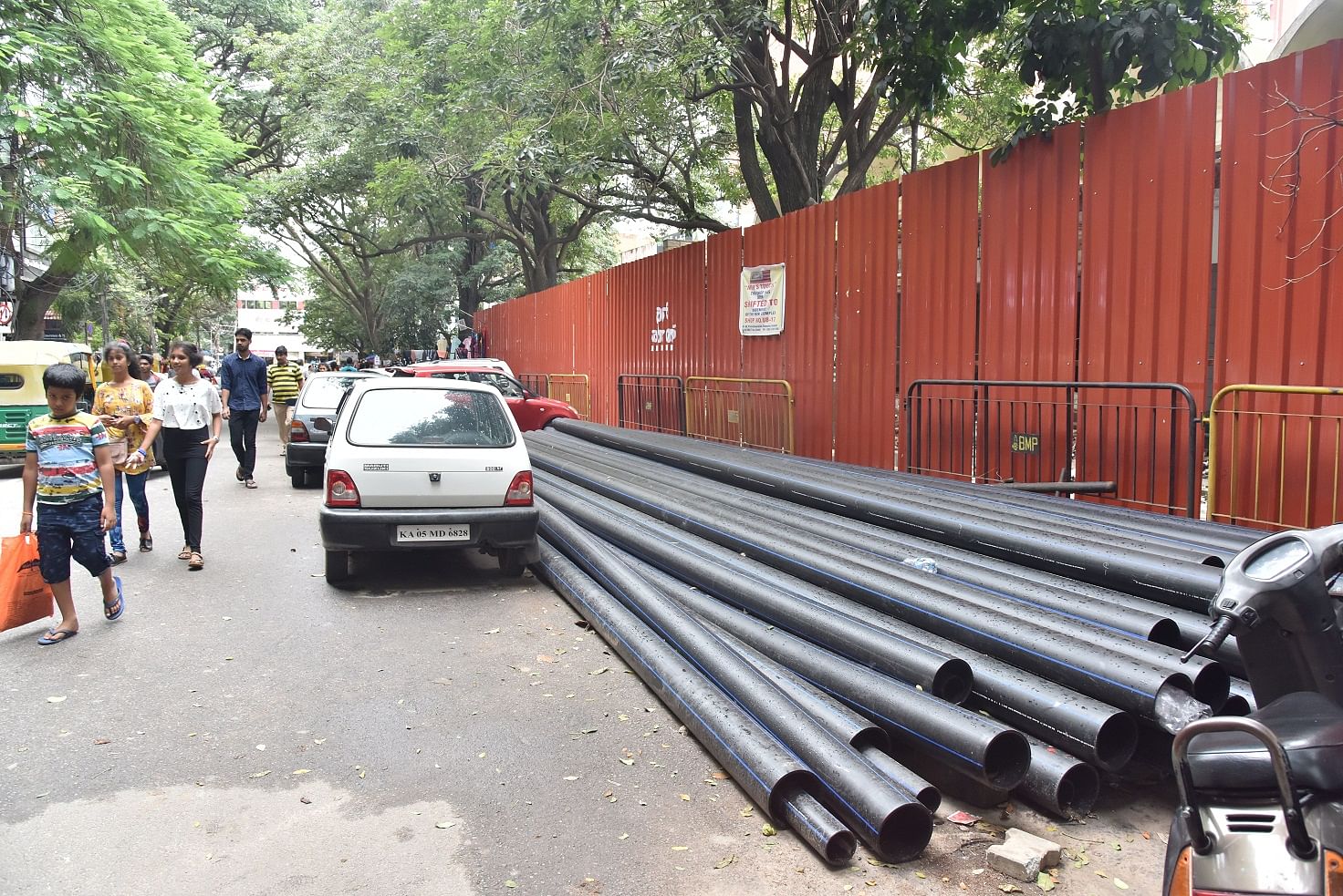 Near Janatha Bazaar in Jayanagar, large metal sheets cut off an entire stretch of footpath, forcing pedestrians to walk on the busy-traffic road. DH Photo by JANARDHAN B K