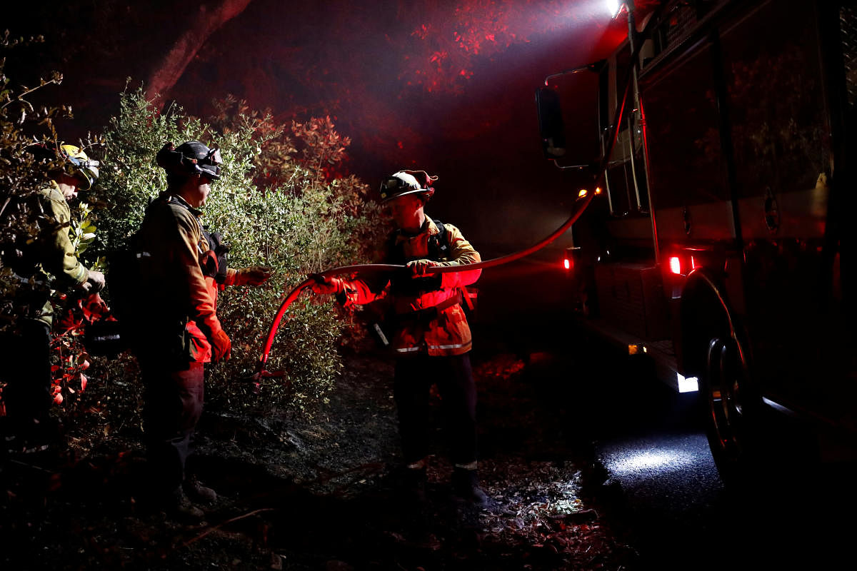 A firefighter passes a hose to douse a hot spot during the Kincade fire in Healdsburg, California. (Reuters Photo)