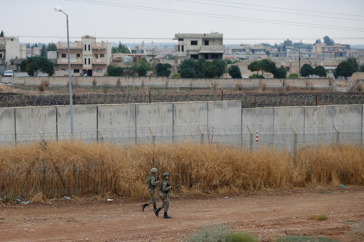 Turkish soldiers patrol along a wall on the border line between Turkey and Syria