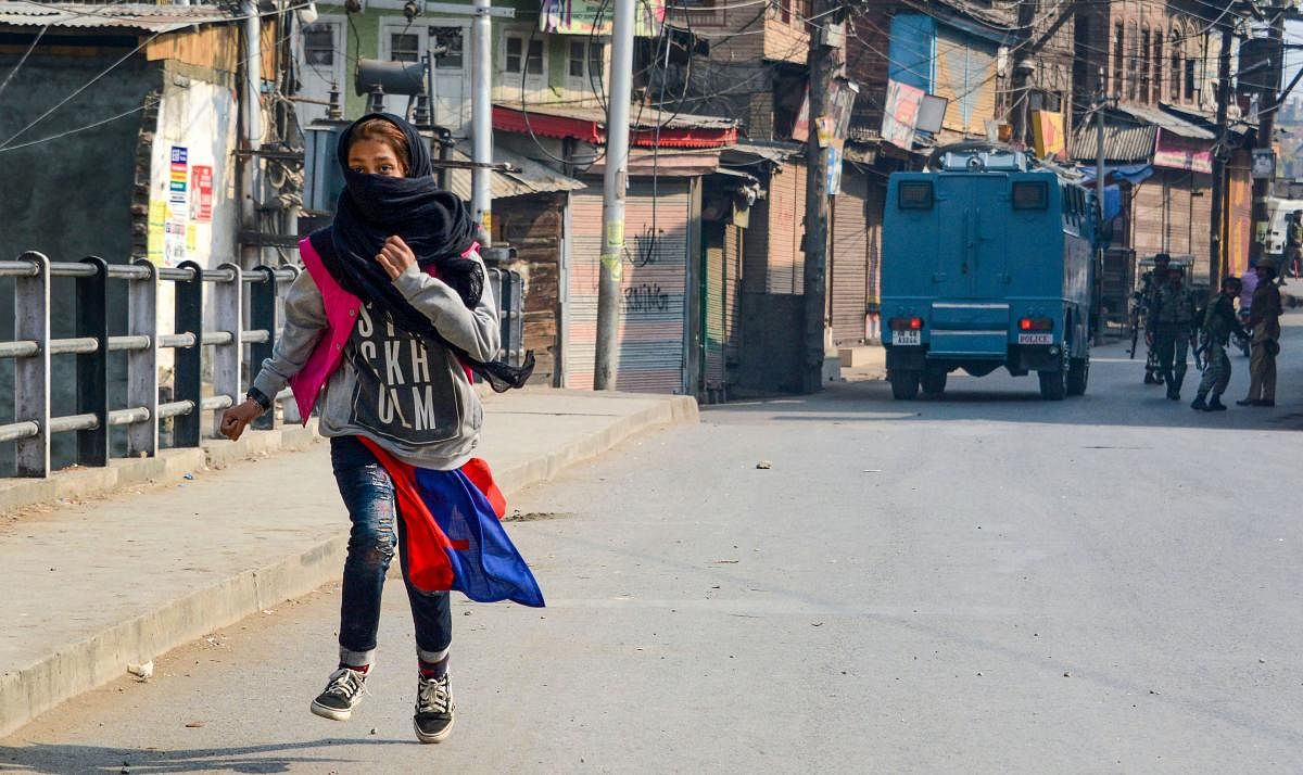 A girl runs for cover after throwing stones during a protest in Srinagar. (PTI Photo)