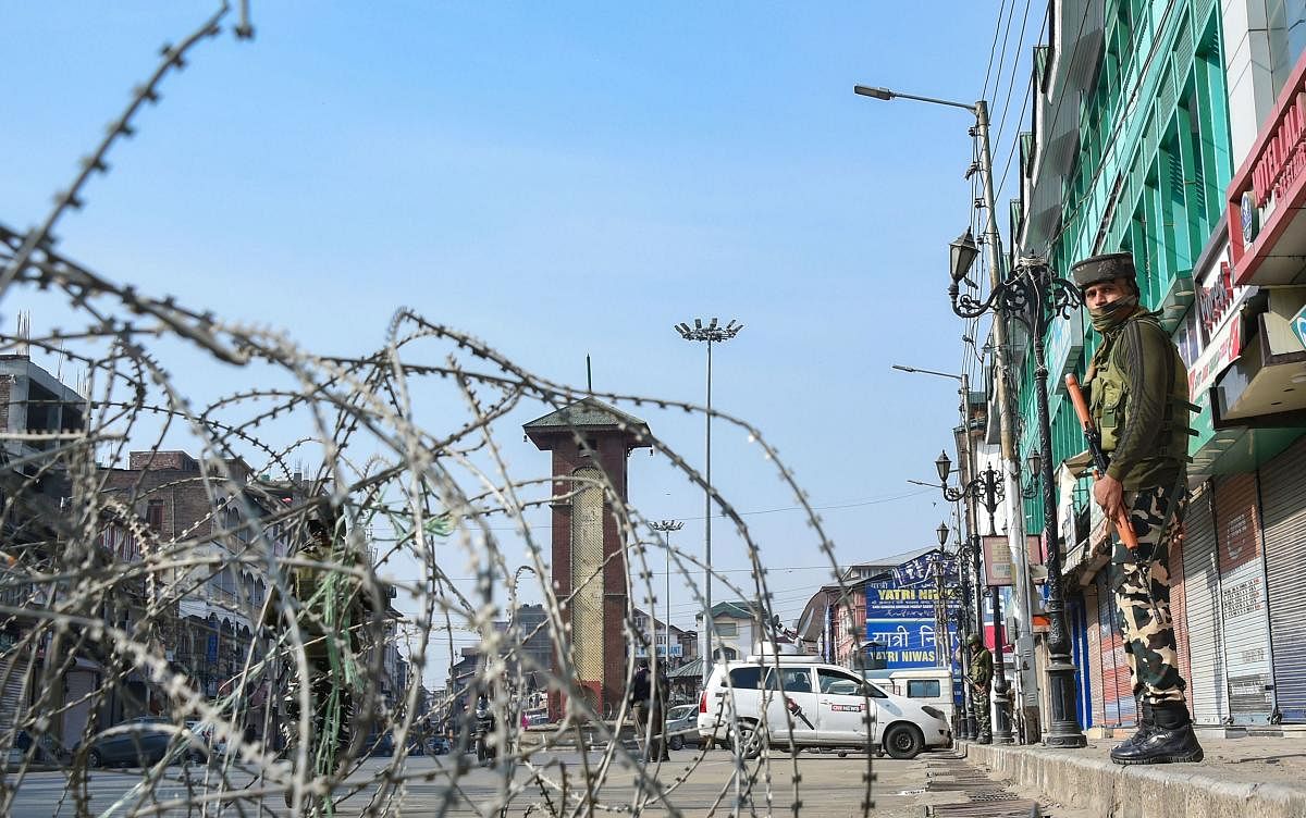 A security jawan keeps vigil as a road is blocked with barbed wires at Lal Chowk after bifurcation of the Jammu and Kashmir state came into existence. (PTI Photo)