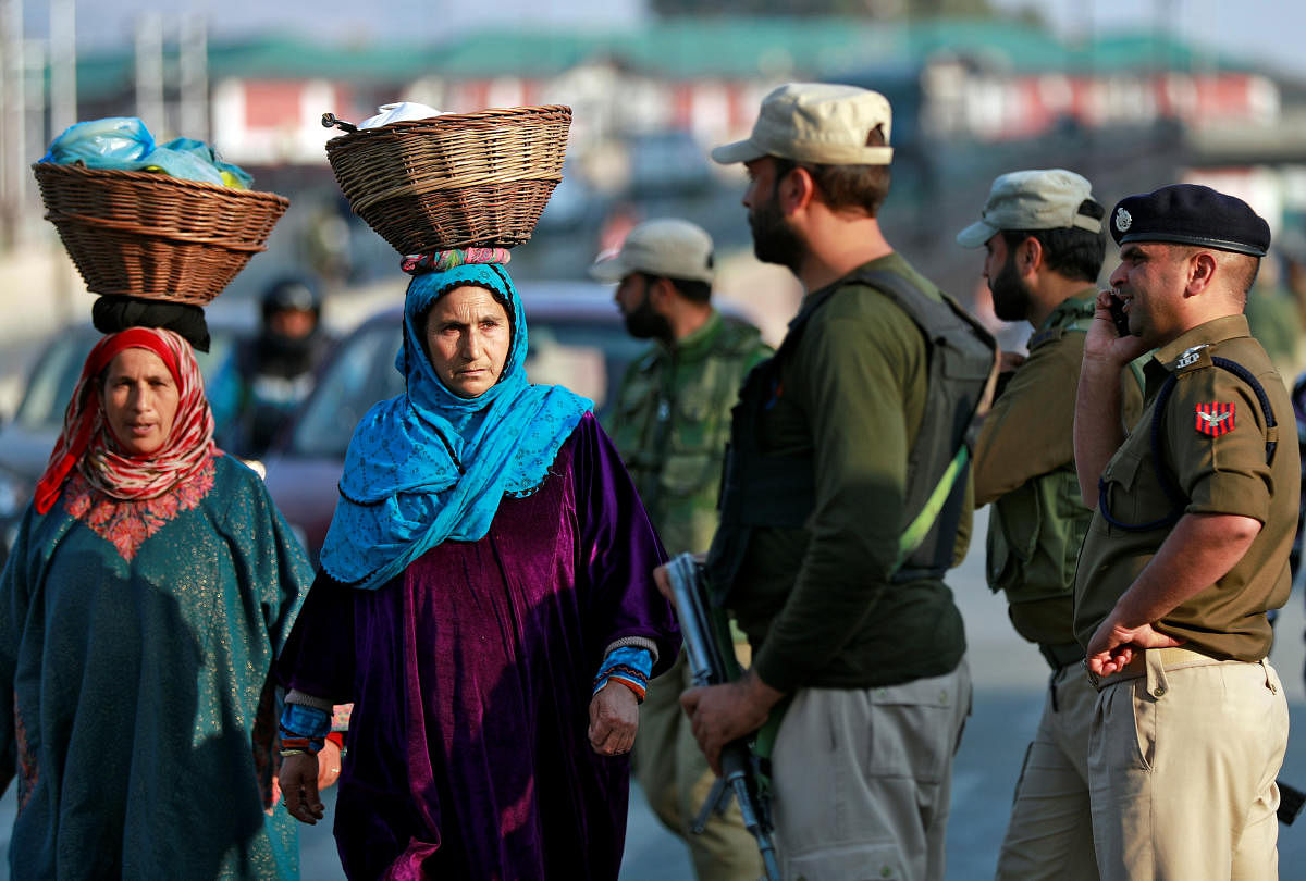 Kashmiri women walk past Indian policemen standing guard in a street in Srinagar October 31, 2019. (REUTERS)
