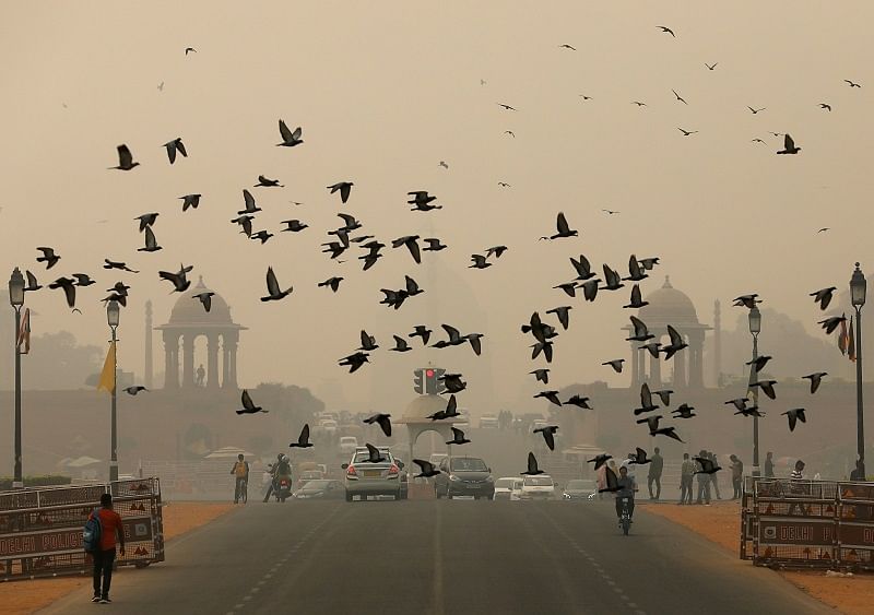 Birds fly as people commute near India's Presidential Palace on a smoggy day in New Delhi. (Reuters Photo)