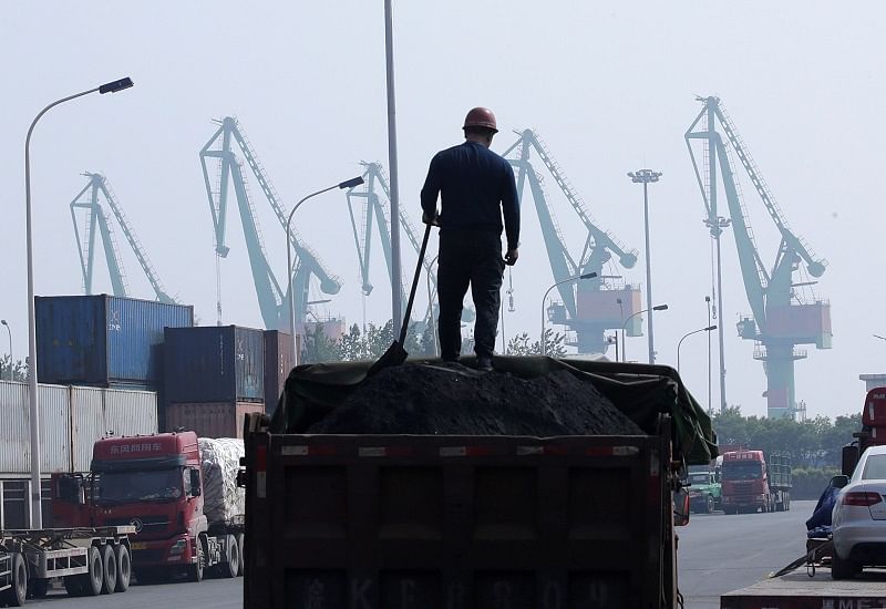A labourer loads coal in a truck next to containers outside a logistics center. (Reuters Photo)