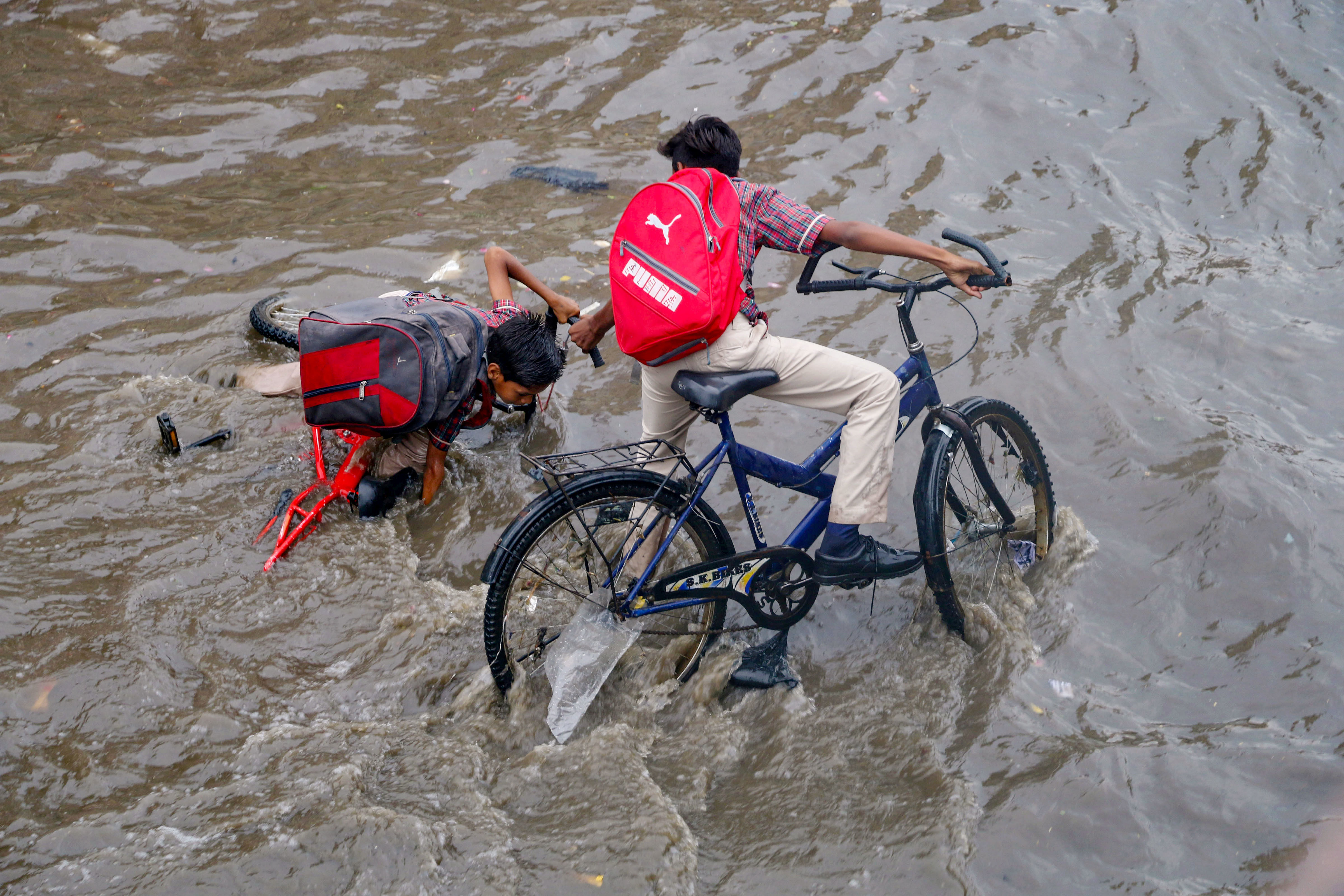 A cyclist loses his balance in a flooded street during rainfall, in Ajmer. (PTI Photo)