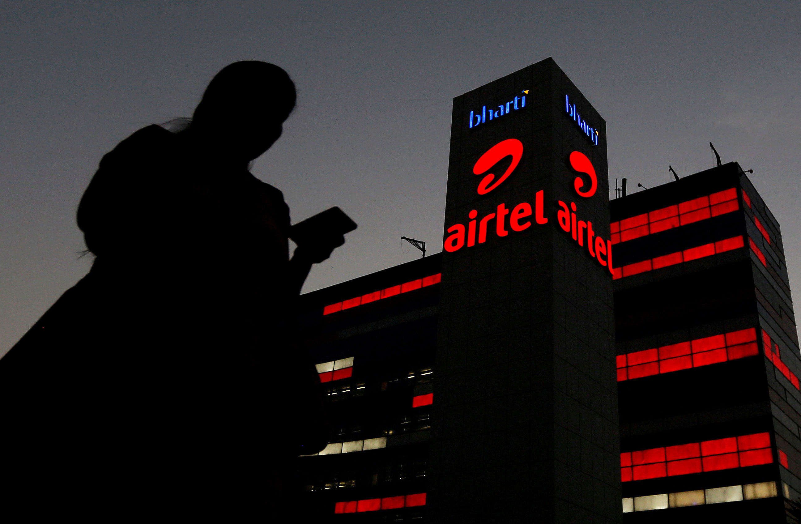 A girl checks her mobile phone as she walks past the Bharti Airtel office building in Gurugram, previously known as Gurgaon, on the outskirts of New Delhi. (Reuters Photo)