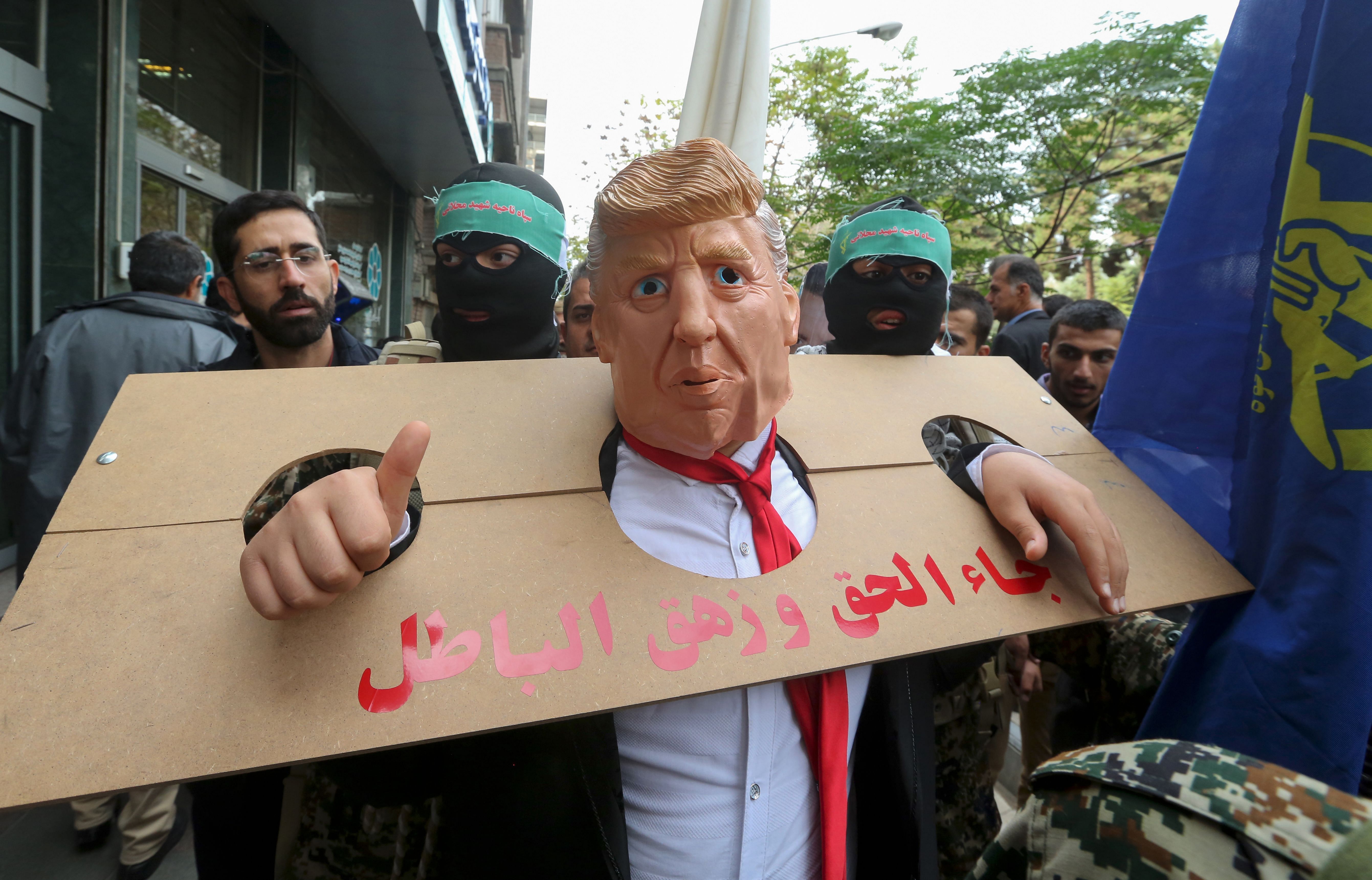 An Iranian protester dressed as US president Donald Trump in a pillory takes part in a rally outside the former US embassy in the capital Tehran. (AFP Photo)
