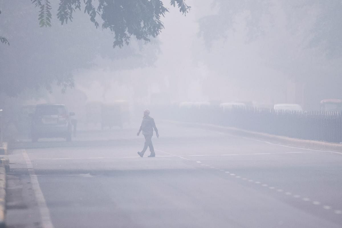 A man crosses a street in smoggy conditions in New Delhi. AFP