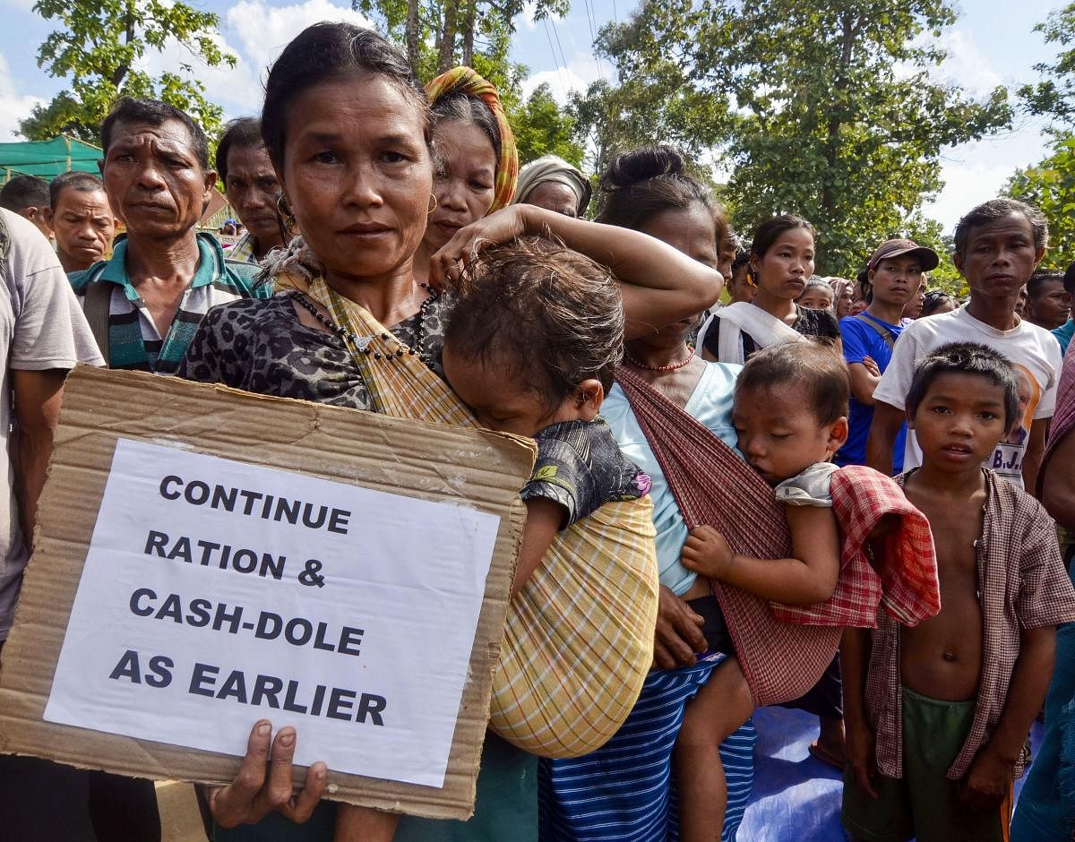 Bru refugees display placards during an indefinite road blockade at Laxmipur (PTI Photo)