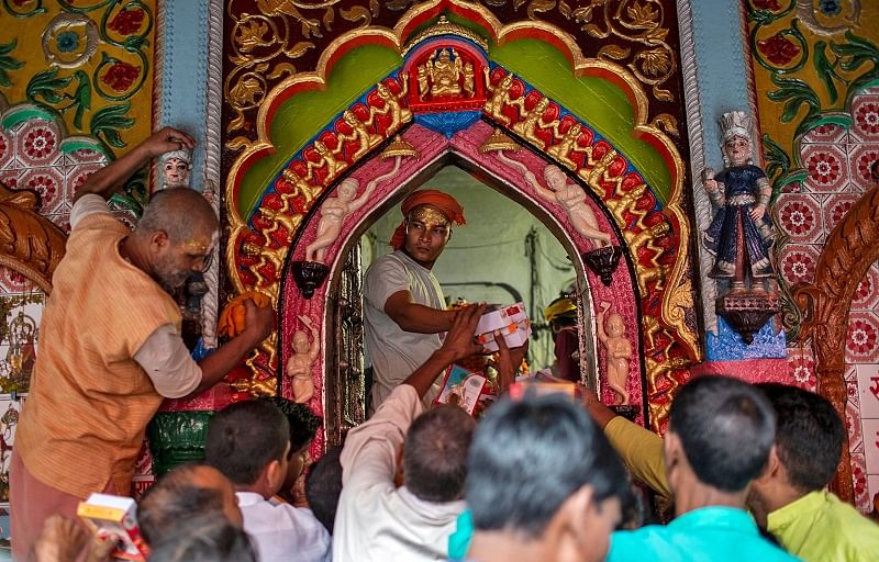 A Hindu priest distributes sweets as "Prasad" (holy offerings) after a prayer session inside a temple in Ayodhya, India. (Reuters Photo)