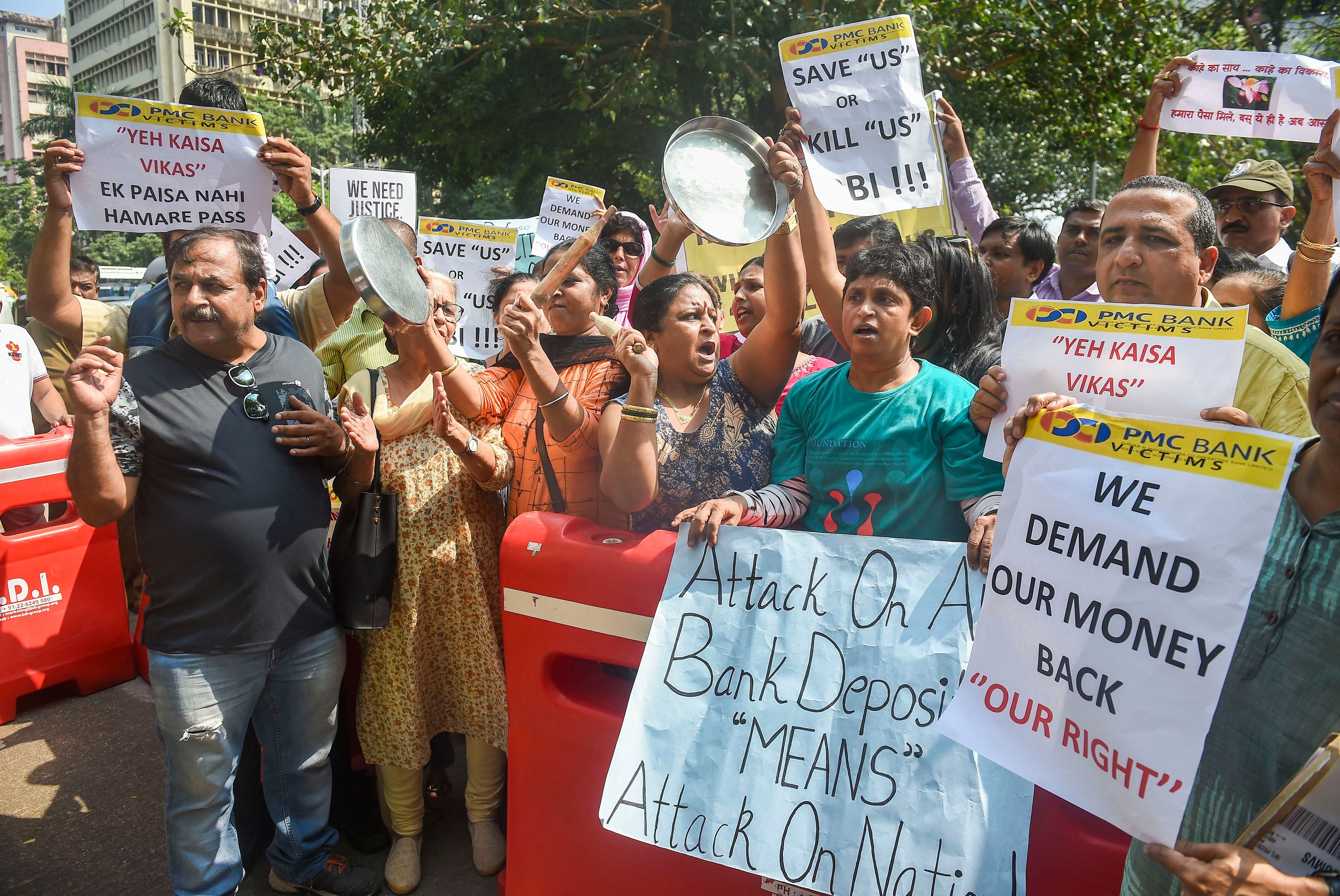PMC Bank account holders hold placards and raise slogans as they protest outside RBI office, at BKC in Mumbai. (PTI Photo)