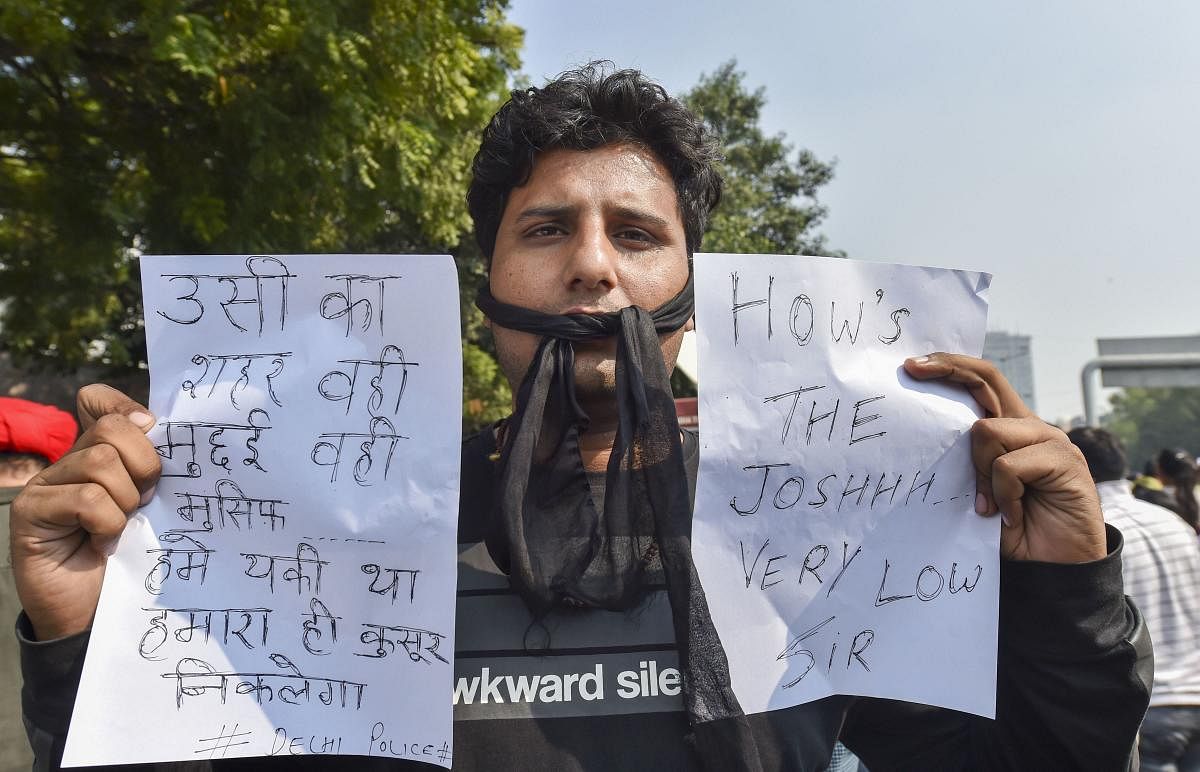 A Delhi Police man displays messages during a protest against the alleged repeated incidents of alleged violence against them by lawyers, at the PHQ in New Delhi on Tuesday. (PTI Photo)