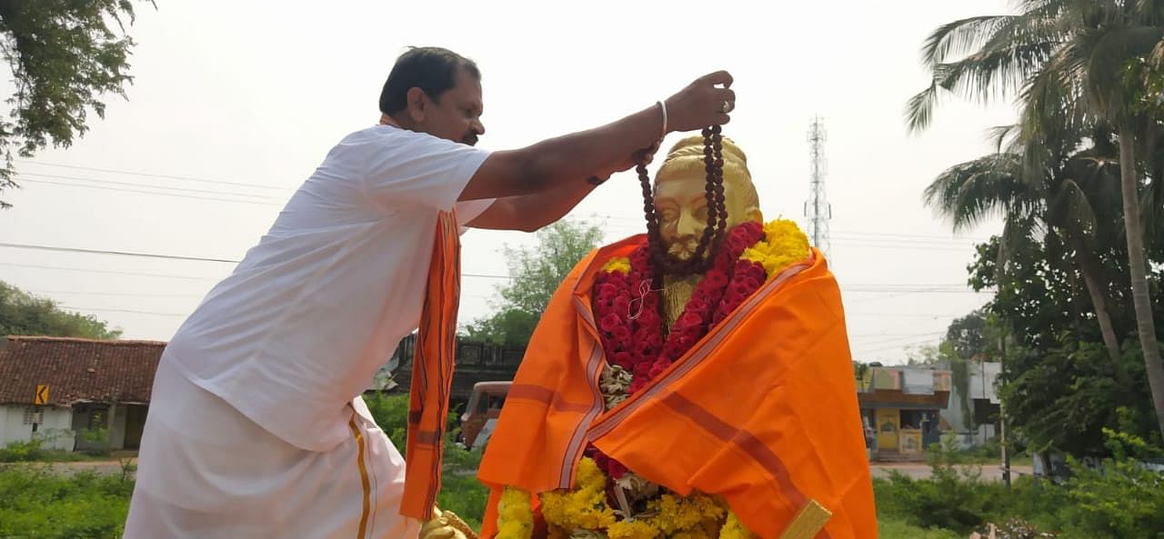 Hindu Makkal Katchi leader Arjun Sampath adoring Thiruvalluvar statue with rudraksha mala in Thanjavur on Wednesday. (DH Photo)