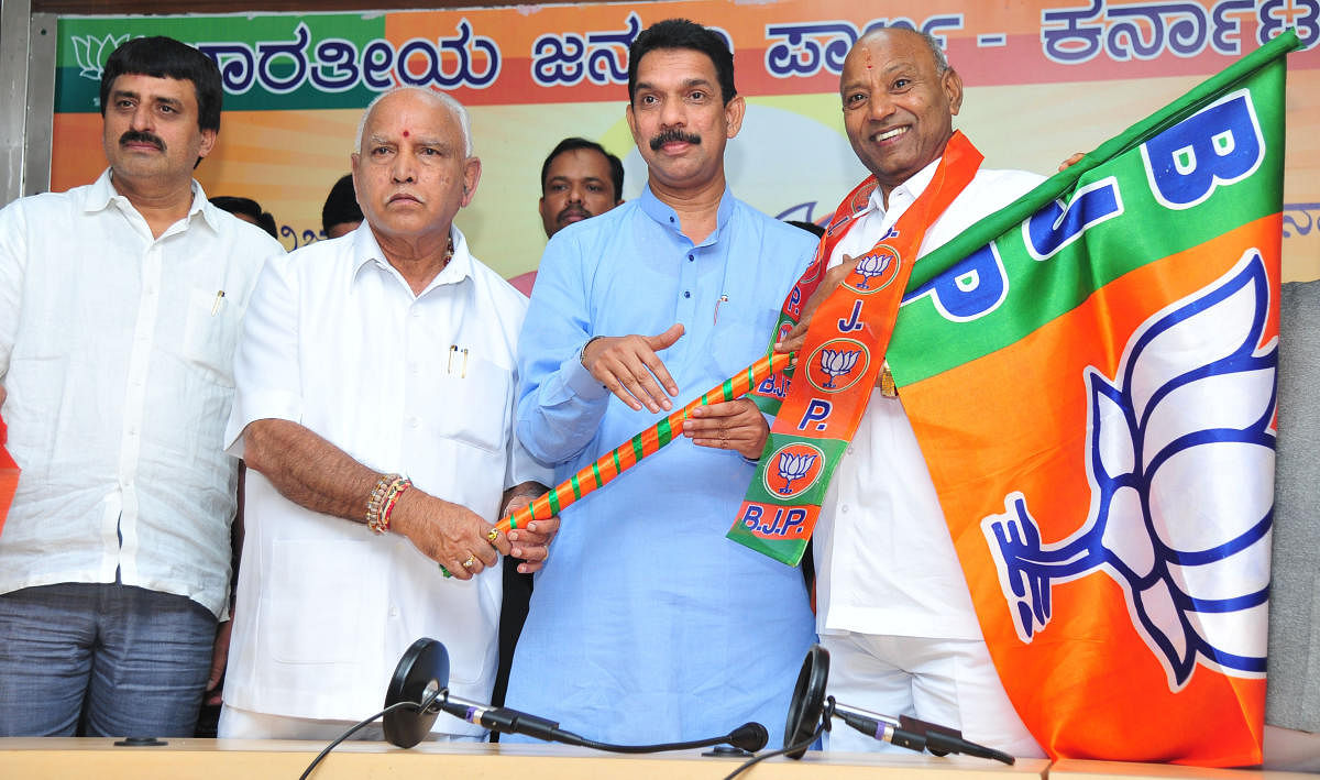 State BJP president hands over BJP flag to Vijayshankar at the party office in Bengaluru on Tuesday. DH Photo