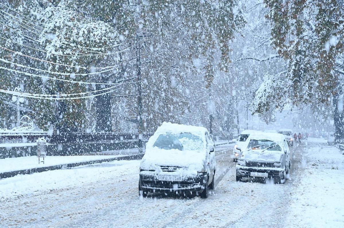 Cars covered in snow drive along a road during a first snowfall in Srinagar on November 7, 2019. (AFP)