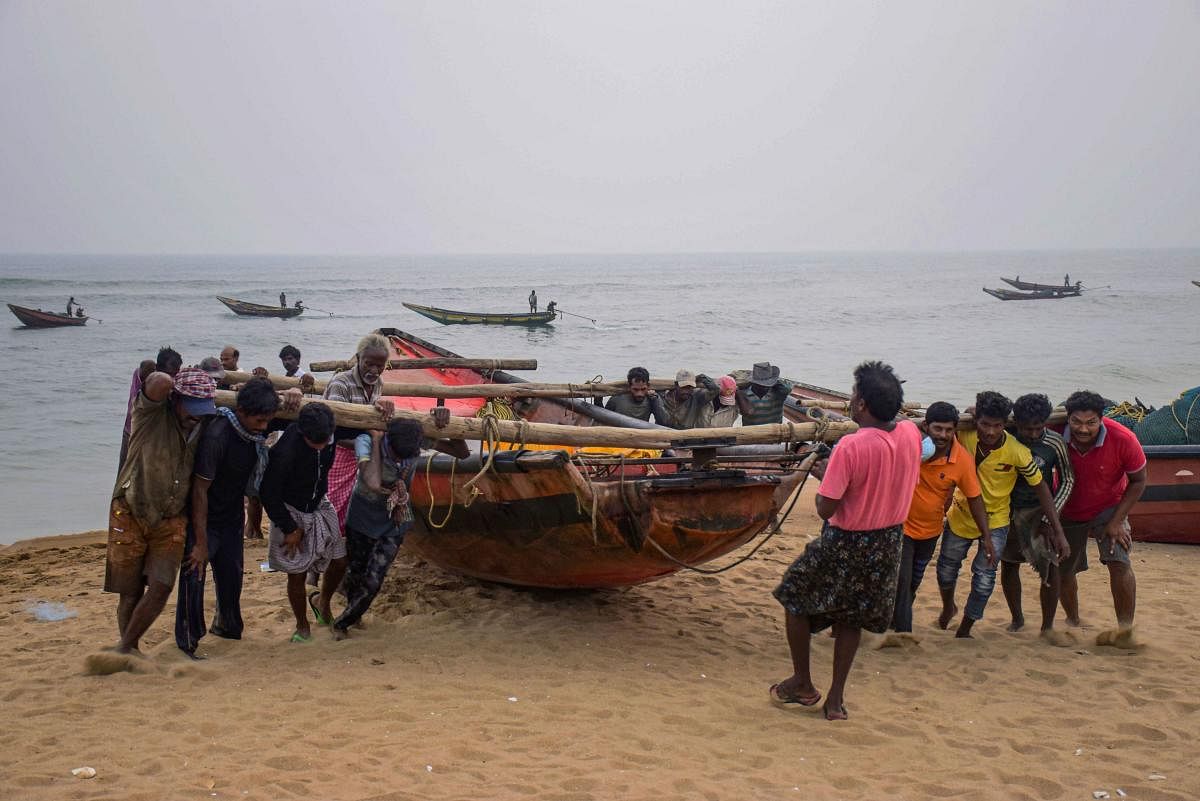 Fishermen pull their boats to away from the sea following Cyclone Bulbul warning, in Puri on Friday. (PTI Photo)