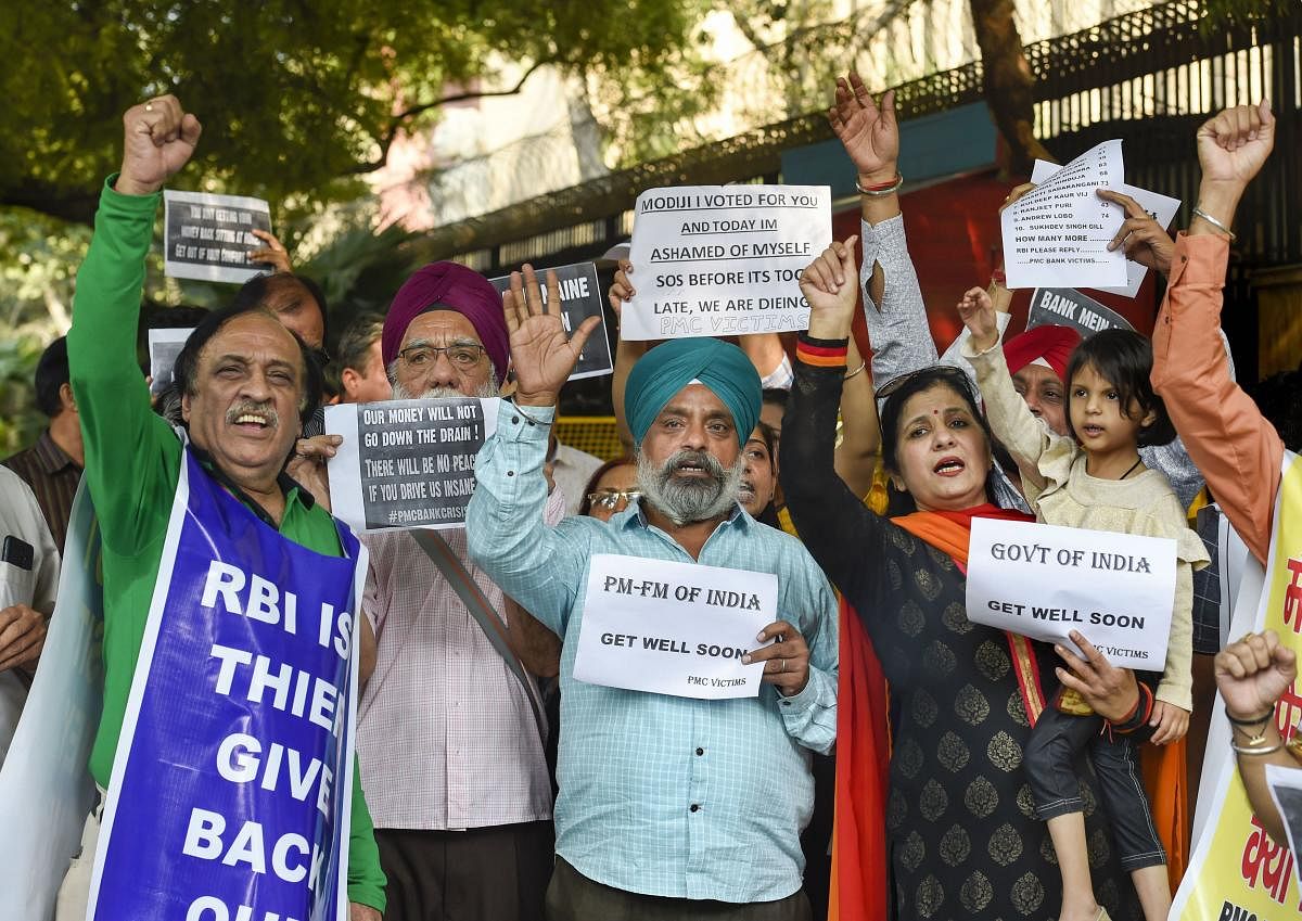 PMC bank account holders display placards as they raise slogans during their protest outside Reserve Bank of India (RBI), in New Delhi. (PTI Photo)