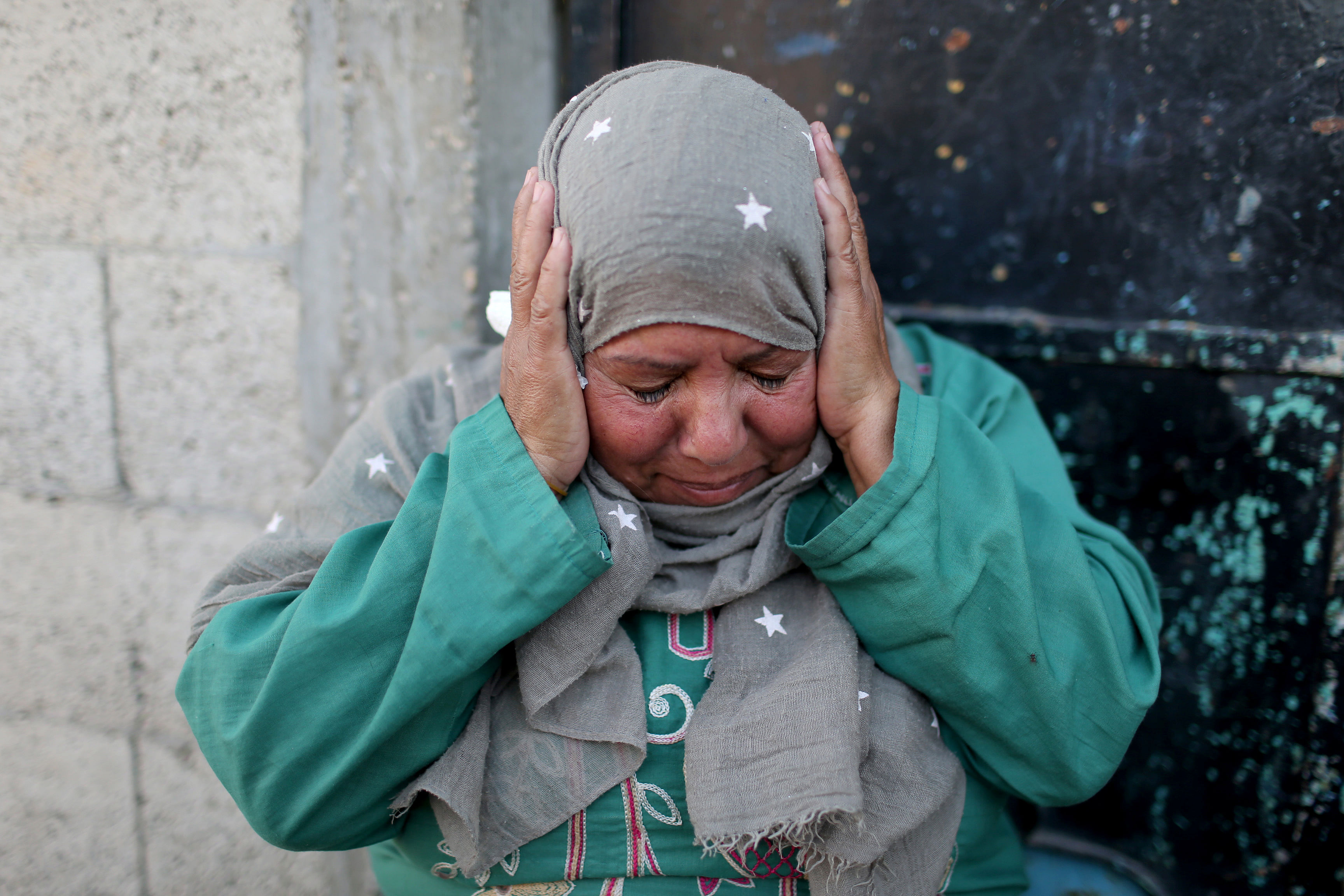 A Palestinian woman reacts as she sits outside her home in the southern Gaza Strip. (Reuters Photo)