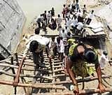 People climb a ladder to get on to the bridge which collapsed during floods in Potnal Halla,  connecting Sindhanur to Manvi,  near Manvi. DH photo/Ana