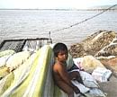 A child sits among belongings shifted to a road after his house was partially submerged, near River Krishna in Vijayawada on Thursday. AP