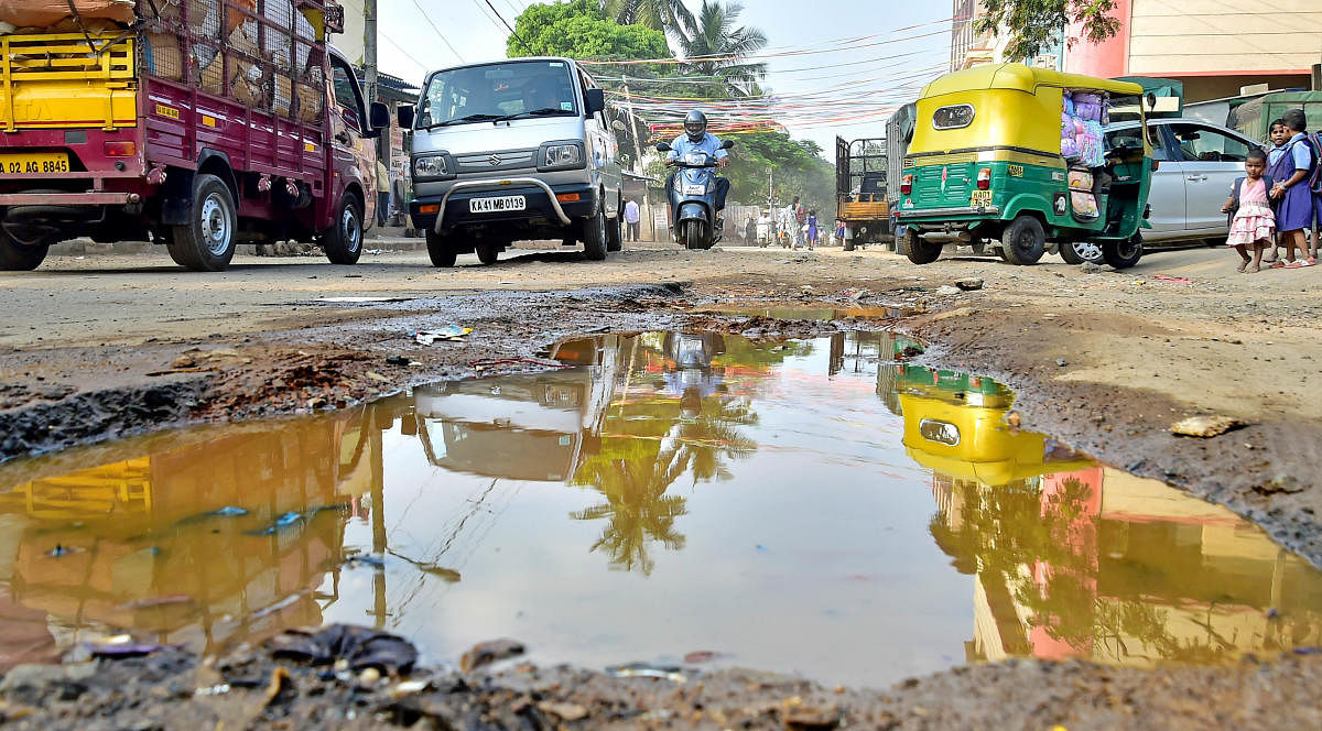 A pothole-filled Cottenpet Main Road in front of Central Crime Branch office on Monday. With the BBMp failing to meet the deadline to fill potholes, there are 1,337 crater yet to be filled up. DH photo/Ranju P