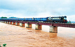 Rain effect: A&#8200;train chugs along on the bridge across River Tunga in Shimoga on Wednesday. (Below) A house which  collapsed due to a landslide at Maranahalli in Sakleshpur taluk. DH Photos