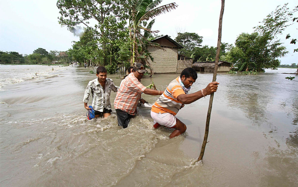 Villagers cross a flooded road at Lachi Bishnupur village in the northeastern Indian state of Assam September 22, 2012. Flood waters of the river Brahmaputra and its tributaries have submerged 13 districts of Assam affecting tens of thousands of people after heavy rains in the region, a media release issued by the state government said. REUTERS