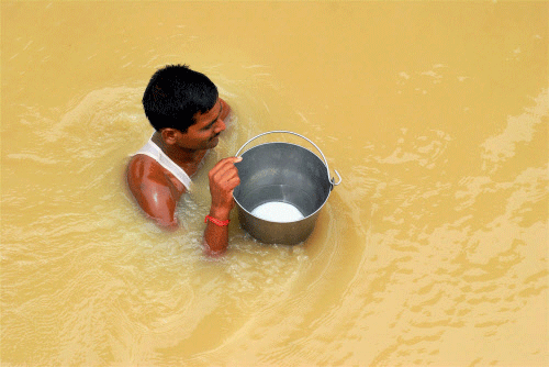 A man wades through flooded water with drinking water in Allahabad, Uttar Pradesh on Friday.PTI Photo