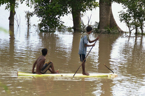 Flood affected people row a banana raft to move to safe place at Bongaon village in Nagaon, Assam on Monday. PTI Photo