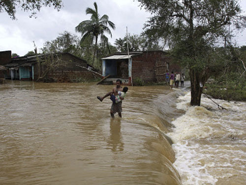 A villager carries a child as he walks through receding flood waters at Banapur in the Khurda district of Odisha, Sunday.  AP