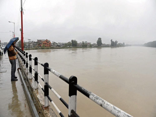 A man watches the rising water level from a bridge in Srinagar. Flood situation today worsened in Kashmir Valley where River Jhelum was flowing above the danger mark even as the Army and NDRF have been called in to assist the administration in relief and rescue efforts in the state where 20 persons have died while another 45 are feared dead. PTI photo