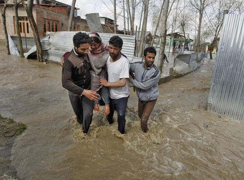 A woman is carried to a safer place from her partially submerged house after incessant rains in Srinagar. Reuters file photo