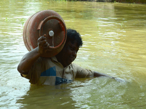 A man carries an LPG cylinder through flood water in Howrah district in West Bengal on Tuesday. PTI Photo
